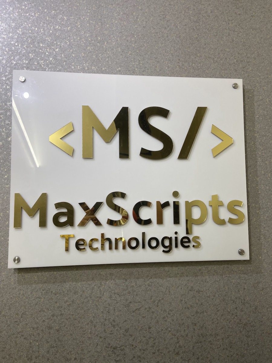 Gold MaxScripts Technologies logo sign on the office wall